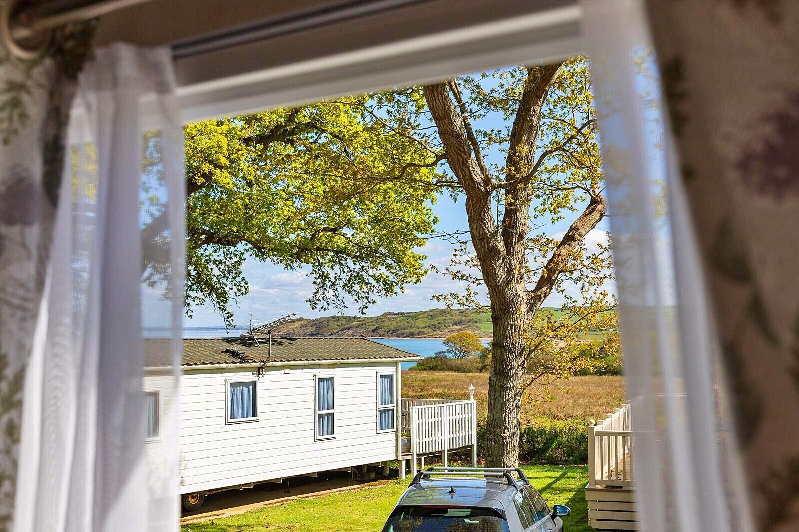 Uma casa branca com garagem, uma árvore em frente e vista para o mar.