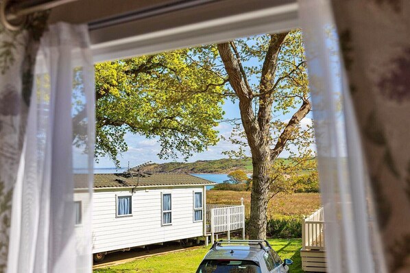 A white house with a garage, a tree in front, and a view of the sea.