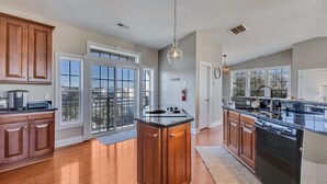 A spacious kitchen with wooden cabinets, a central island, and a large window overlooking a balcony.