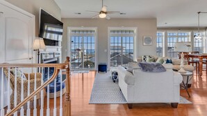 A spacious living area with a large sofa, a dining table, and a staircase leading to an upper level.