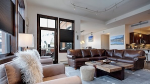 A modern living room with a leather sofa, a coffee table, and a large window.