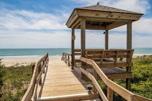 Ein hölzerner Strandpavillon mit einer Holzterrasse, die darauf führt, mit Blick auf den Ozean.