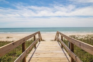 Una pasarela de madera que conduce a una playa, con cielo despejado.