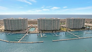 Ein Hochhaus-Hotel mit mehreren Balkonen, einer Marina mit Anlegestellen und einem Poolbereich.
