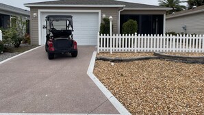 A residential house with a garage, a white picket fence, and a golf cart parked in the driveway. - Stylish Home in Duval w/Granite, Tile Floors, Glass Lanai & Gas Golf Cart! (The Villages)