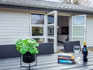 An outdoor seating area with a table, a potted plant, a wine bottle, and books. - 4 Star Holiday Home in Borkop (Borkop)