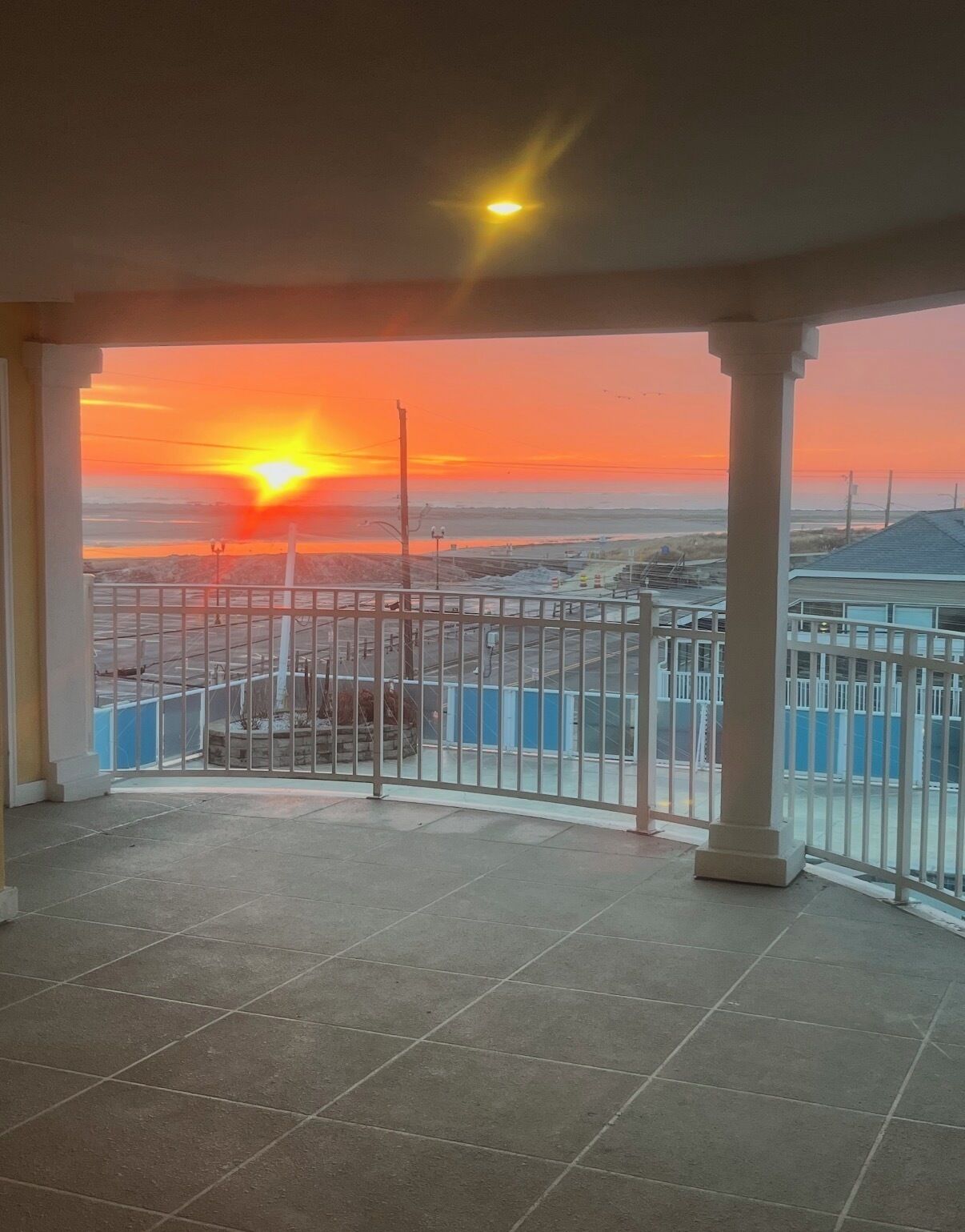 A balcony with a view of a sunset over a flat landscape.