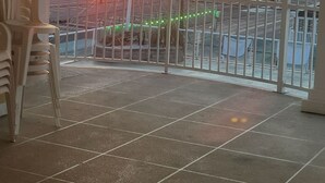 A balcony with a view of the sunset over the ocean, a tiled floor, and a stack of plastic chairs. - Steps Away From All the Fun (Wildwood)