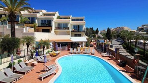 A hotel with a swimming pool, sun loungers, and a view of the surrounding buildings. - Townhouse 12 with amazing sea views (Ferragudo)