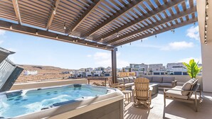 Eine Dachterrasse mit Whirlpool, Sitzgelegenheiten im Freien und Blick auf die umliegenden Gebäude.