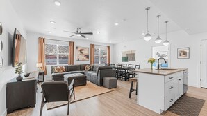 Un vaste espace de vie comprenant un grand canapé, une table à manger et une cuisine dotée d’un îlot central.