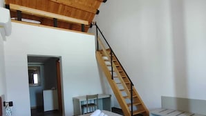 A bedroom with two beds, a wooden ceiling, a staircase, and a small desk area. - Foresteria Mongerrati (Isnello)