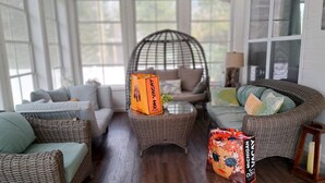 A cozy living room with wicker furniture, a large window, and a decorative chair.