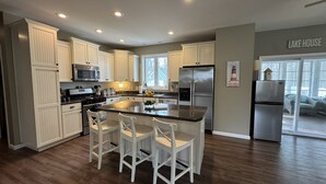 A modern kitchen with white cabinetry, stainless steel appliances, and a central island with bar stools.