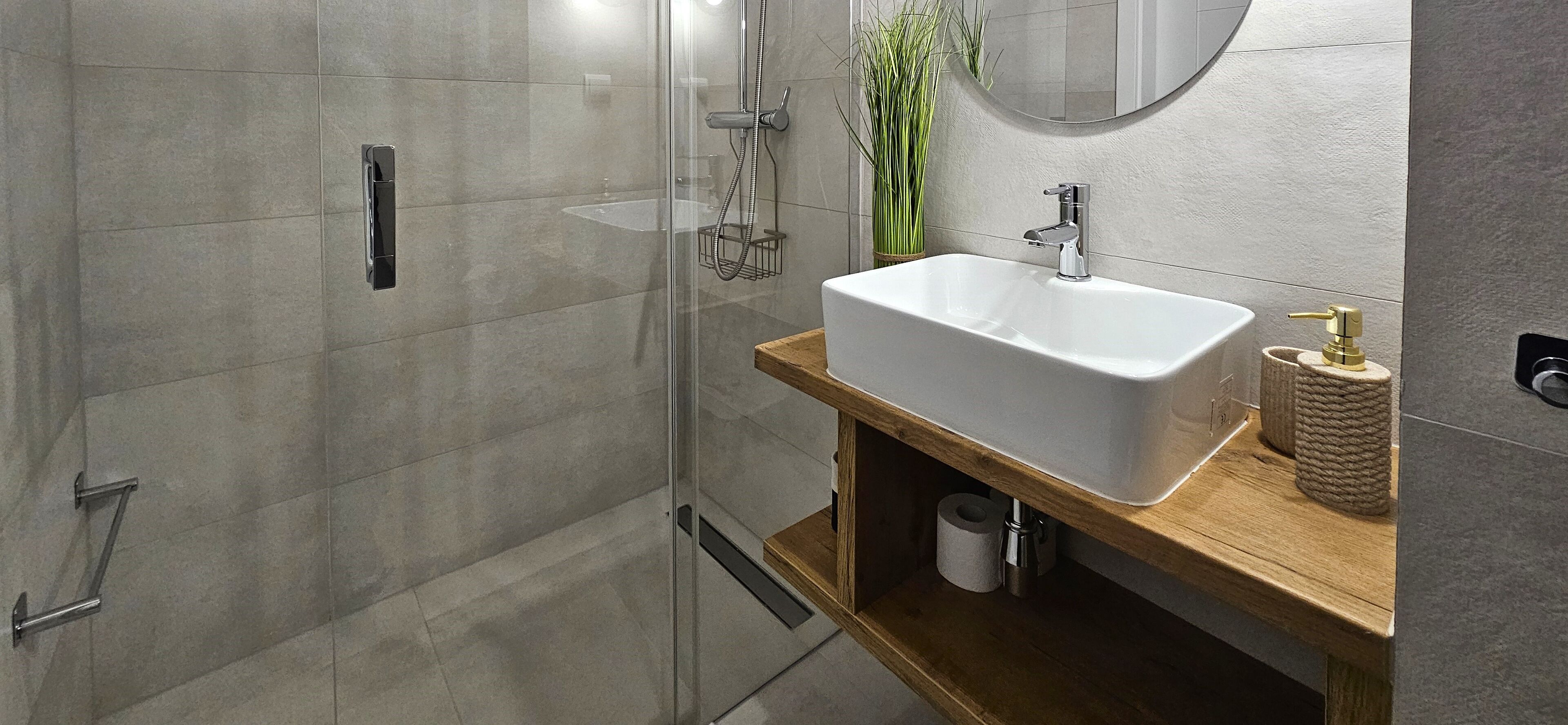 Une salle de bain moderne avec une douche à parois de verre, un lavabo blanc et un meuble-lavabo en bois.