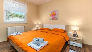 Ein Schlafzimmer mit einem Bett, zwei Nachttischen, einem Fenster mit Blick und einem Bild an der Wand.
