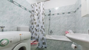 Ein Badezimmer mit Waschmaschine, Toilette, Badewanne und Dusche.
