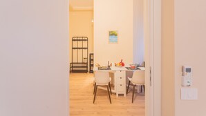 A dining area with a table set for two, a chair, a small plant, and a wall-mounted device. - Breva Apartment Nearby Como S G Train Station (Como)