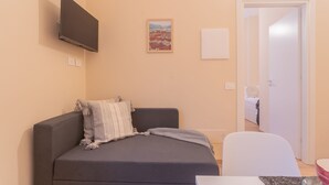 A small, modern room with a bed, a TV mounted on the wall, and a door leading to another room. - Breva Apartment Nearby Como S G Train Station (Como)