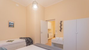 A modern bedroom with two beds, a small kitchenette, and a wardrobe. - Breva Apartment Nearby Como S G Train Station (Como)