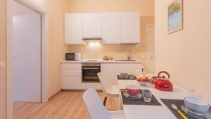 A compact kitchen with white cabinets, a microwave, and a red kettle on the counter. - Breva Apartment Nearby Como S G Train Station (Como)