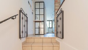 A staircase with beige steps and black metal railings, leading to a room with a large window and a view of the outside. - Vacation Family Home in Tremezzo by Rent all Como (Tremezzina)