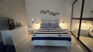 Un dormitorio moderno con cama, mesitas de noche, cómoda y espejo.