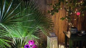 Ein Holztisch mit floraler Dekoration, Laternen und einem Bambus-Hintergrund.