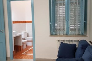Un baño con inodoro, lavabo y ventana con cortinas.