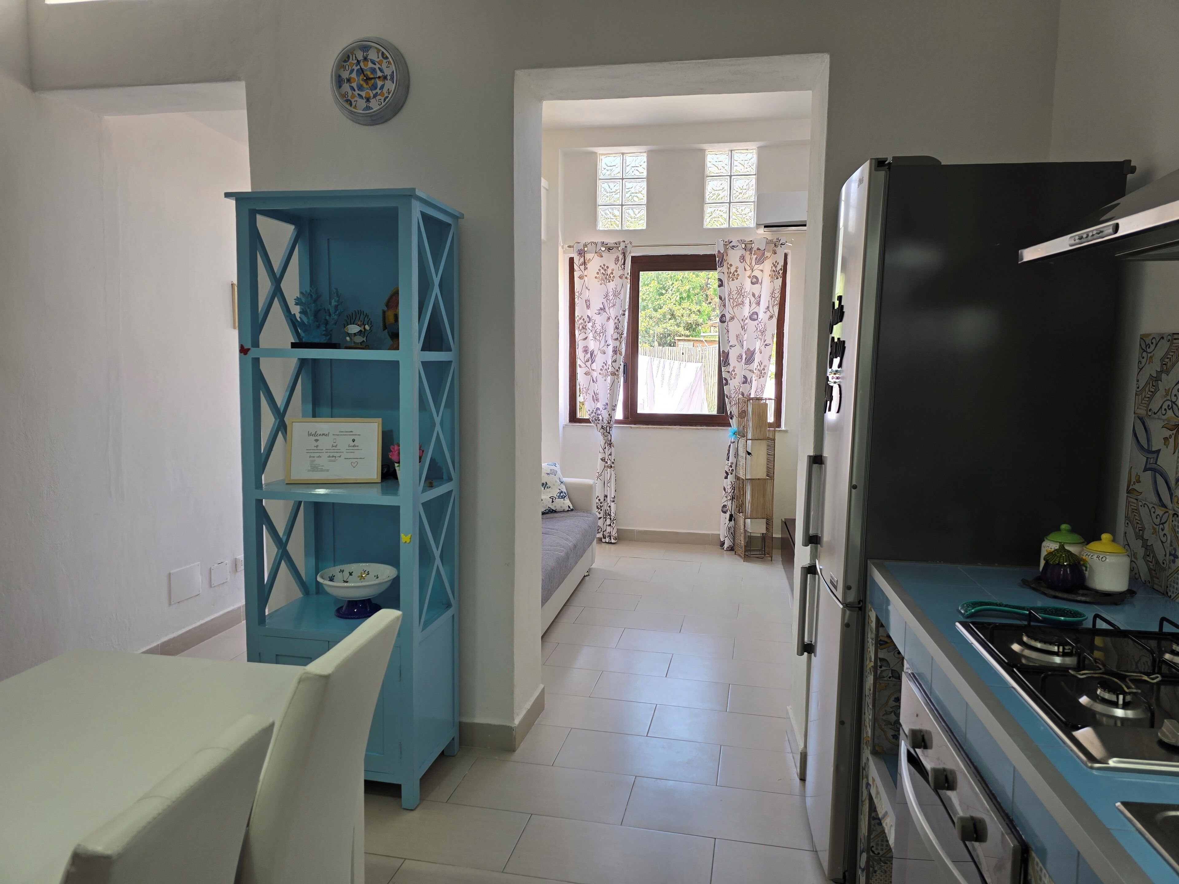 Una cocina con un armario azul, una mesa blanca y un refrigerador negro.
