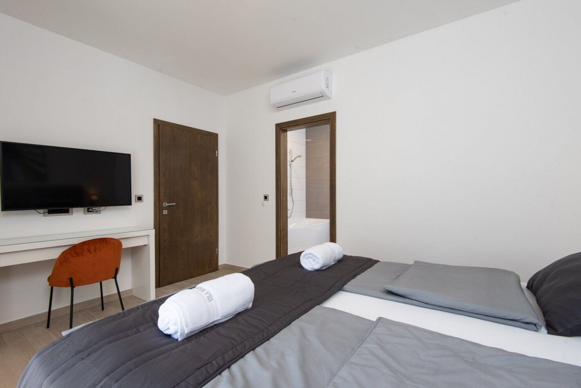 Une chambre d’hôtel équipée d’un lit, d’un bureau, d’une télévision et d’un espace douche.