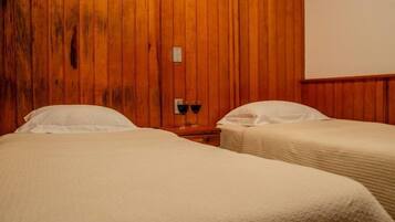 Two single beds with white pillows and duvets, a nightstand, and wine glasses.