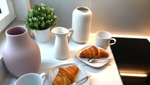 A kitchen counter with a croissant, a pitcher, a mug, a vase, and a potted plant. - Studio Paris (Ivry-sur-Seine)
