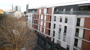 A modern multi-story building with a mix of white and red brick facades, large windows, and balconies. - Studio Paris (Ivry-sur-Seine)