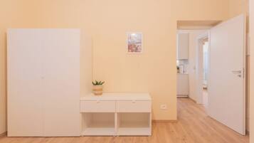 Una camera da letto con un letto, un armadio bianco, un comodino con una pianta e una porta che dà su un bagno.