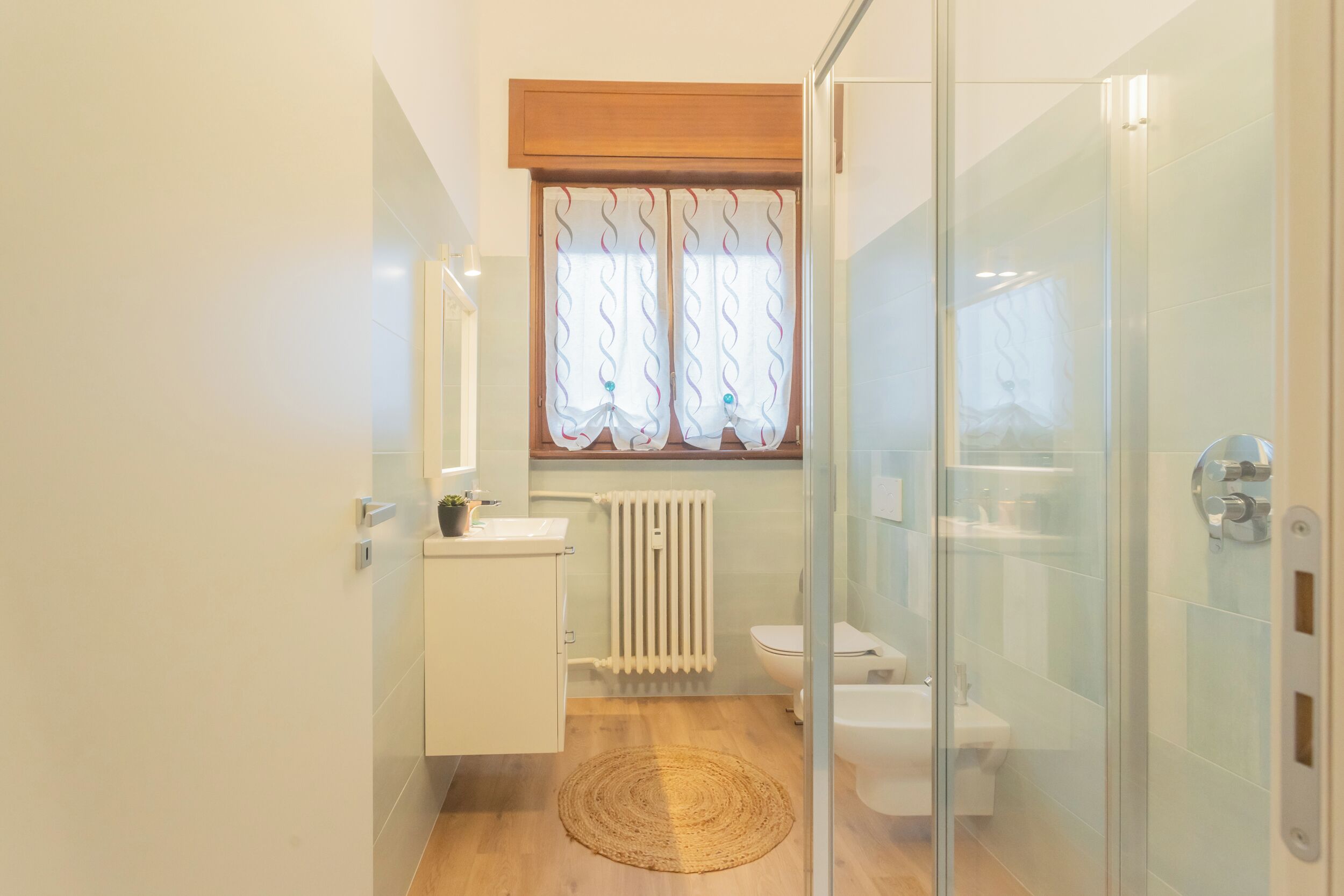 Une salle de bain moderne avec une douche à parois de verre, un lavabo blanc, des toilettes et un radiateur.