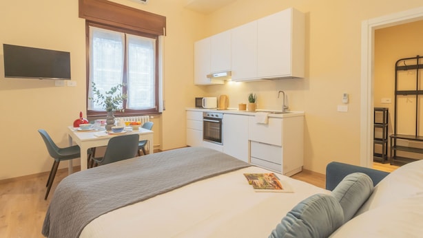 Una camera da letto compatta con un letto, un comodino e un angolo studio con una sedia.