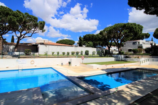 A swimming pool with two separate sections, surrounded by trees and buildings. - Albufeira Açoteias Villa by Homing (Albufeira)