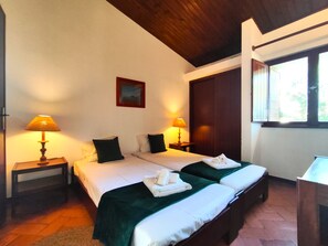 A hotel room with two beds, a wooden ceiling, a painting on the wall, and a window with blinds. - Albufeira Açoteias Villa by Homing (Albufeira)