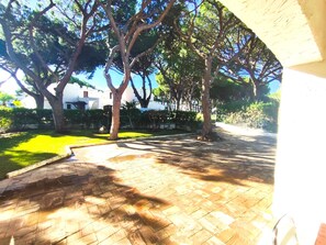 A paved pathway with trees and a grassy area, leading to a building with a white facade. - Albufeira Açoteias Villa by Homing (Albufeira)