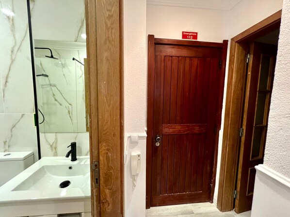 A bathroom with a white sink, a mirror, and a wooden door. - Vilamoura Nautilus With Pool by Homing (Loulé)