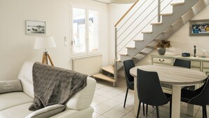 A modern living room with a staircase, a dining area, and a large window. - 50 m from the beach, pretty Breton house in the heart of the Pink Granite Coast (Trégastel)