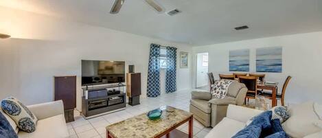 A living room with a sofa, coffee table, TV, and a ceiling fan.