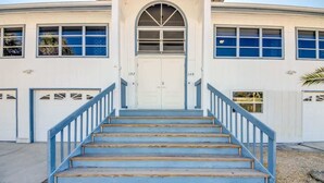 A building with a central entrance, two garage doors, and a staircase leading up to the entrance. - 190 Anchorage Unit A Spacious Unit near Beach (Fort Myers Beach)