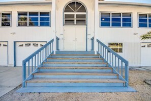 A building with a central entrance, two garage doors, and a staircase leading up to the entrance. - 190 Anchorage Unit A Spacious Unit near Beach (Fort Myers Beach)