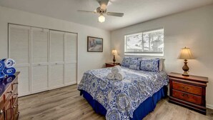 A bedroom with a bed, a ceiling fan, a window with blinds, a nightstand, and a dresser. - 190 Anchorage Unit A Spacious Unit near Beach (Fort Myers Beach)