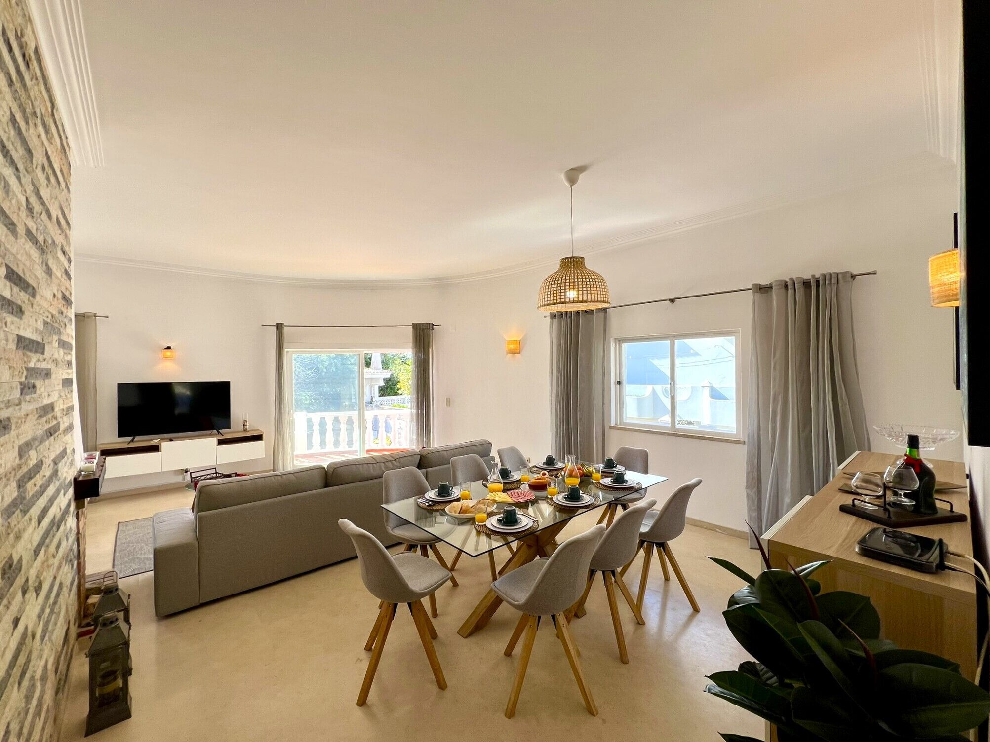 Un salon moderne avec un canapé, une table à manger et des chaises, un téléviseur et une vue sur le balcon.