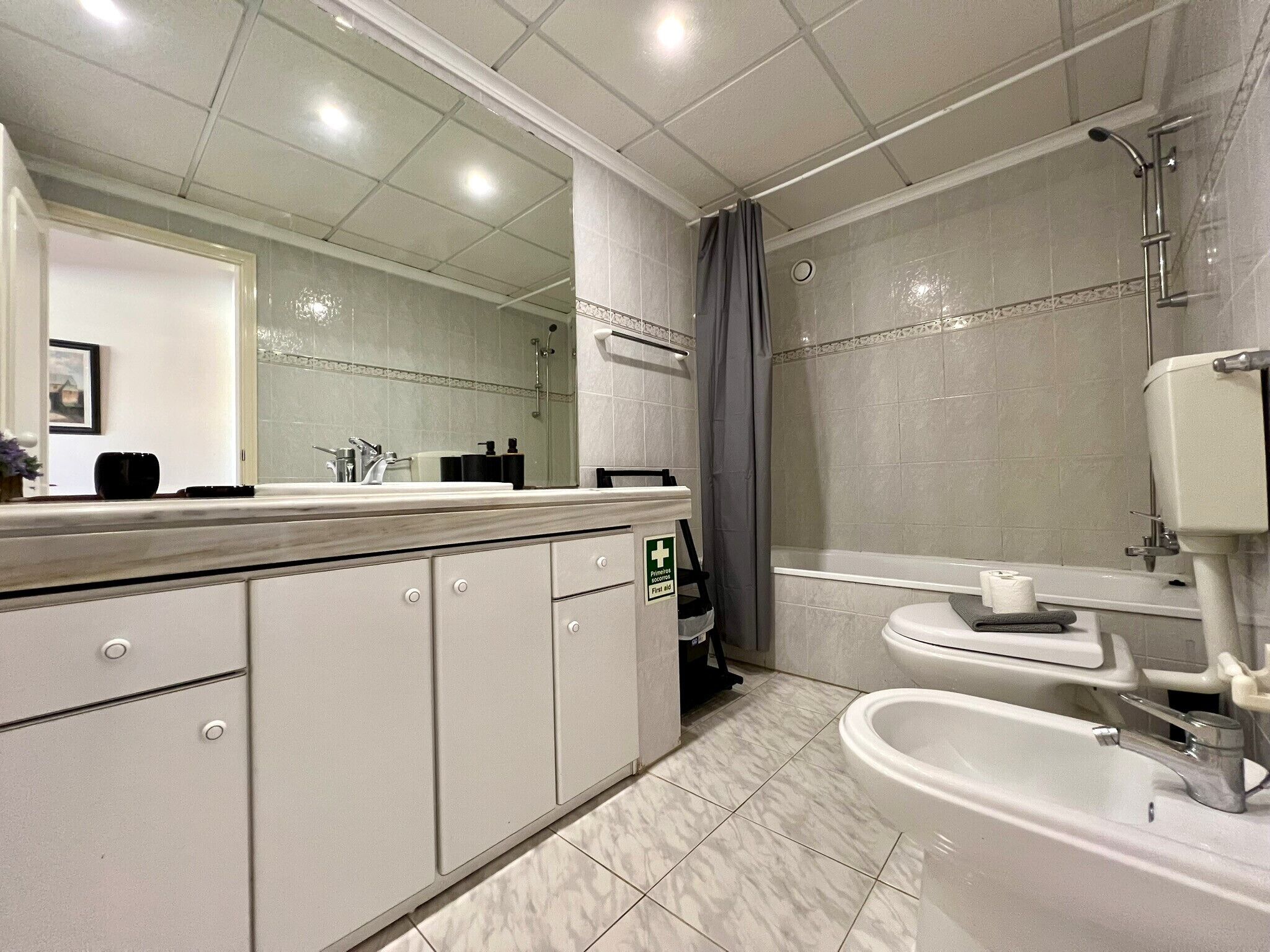 A modern bathroom with a large mirror, a shower, and a toilet.