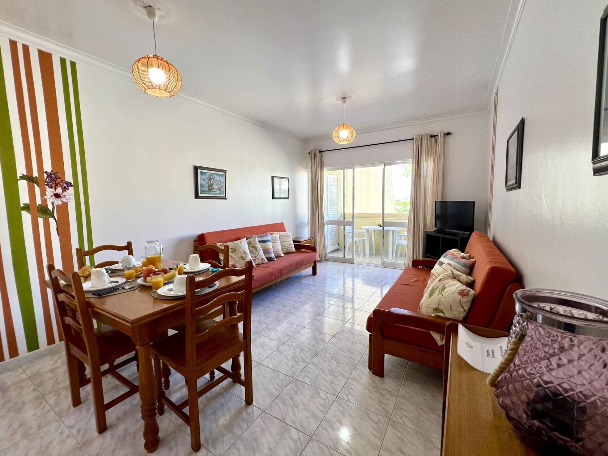 A living room with a dining table, chairs, a sofa, and a TV.