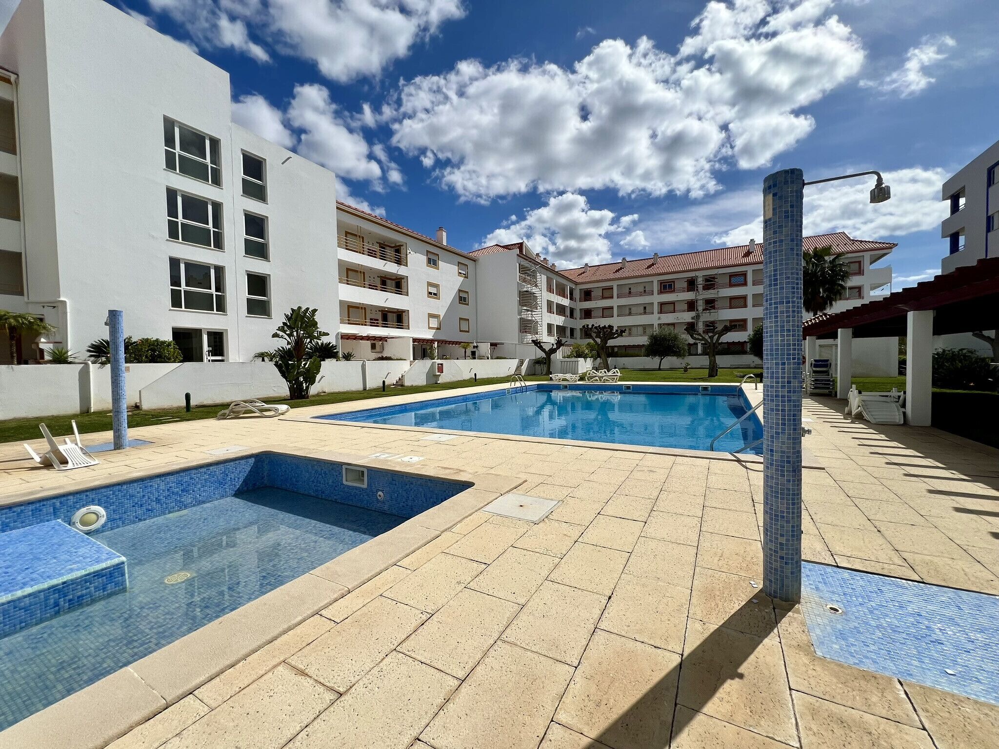Una piscina con bordi piastrellati, circondata da un'area pavimentata con un lampione.